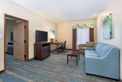 a hotel room with a couch and a television at La Quinta by Wyndham Dallas Grand Prairie South in Grand Prairie