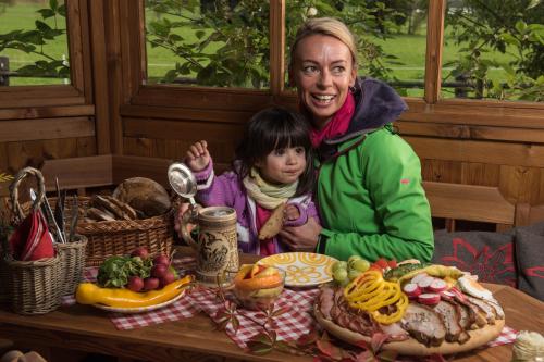 a woman and a child sitting at a table with food at Landhaus Rohrmoser in Werfenweng