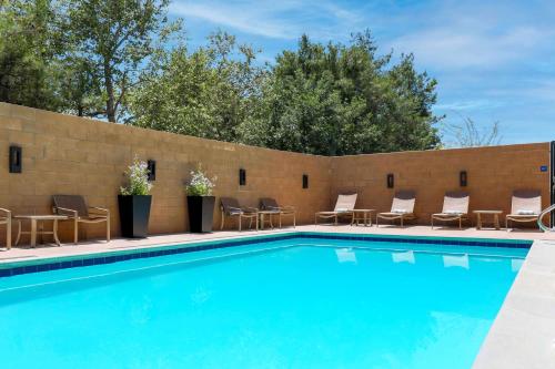 a swimming pool with chairs and a brick wall at Hyatt House Davis in Davis