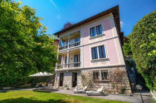 a large pink building with chairs in a yard at Charming & Luxury Villa Como Lake in Como
