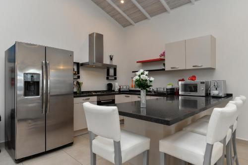 a kitchen with a stainless steel refrigerator and white chairs at Boutique Hotel Swiss Paradise Aruba Villas and Suites in Palm-Eagle Beach
