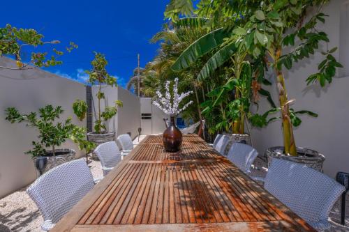 a long wooden table with chairs and a vase on it at Boutique Hotel Swiss Paradise Aruba Villas and Suites in Palm-Eagle Beach