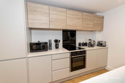 a kitchen with white cabinets and stainless steel appliances at Aurora Heights by Grandeur Property in Poole