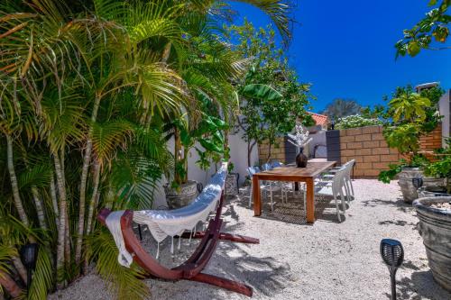 a patio with a table and chairs and palm trees at Boutique Hotel Swiss Paradise Aruba Villas and Suites in Palm-Eagle Beach