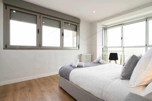 a bedroom with a large bed with windows at El Séptimo, Apartamento in Gijón