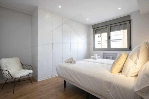 a bedroom with a large bed and a chair at El Séptimo, Apartamento in Gijón