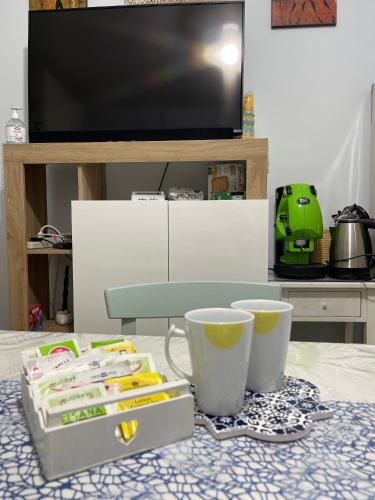 a table with a tv and two cups on it at Oasi della pace in Bisceglie