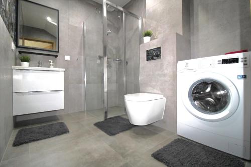 a bathroom with a washing machine and a sink at Apartament MiMi - Dziwnówek Horizon Park , 2 sypialnie i salon in Dziwnówek