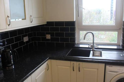 a kitchen with a sink and a black tiled wall at Beautiful 1-Bed Apartment in London in London