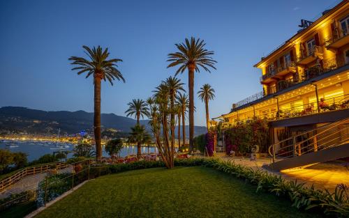 a resort with palm trees and a lawn in front of a building at Hotel Continental in Santa Margherita Ligure