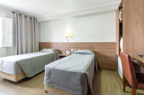 a hotel room with two beds and a table at Hotel Dom Rafael Executivo in Santa Maria