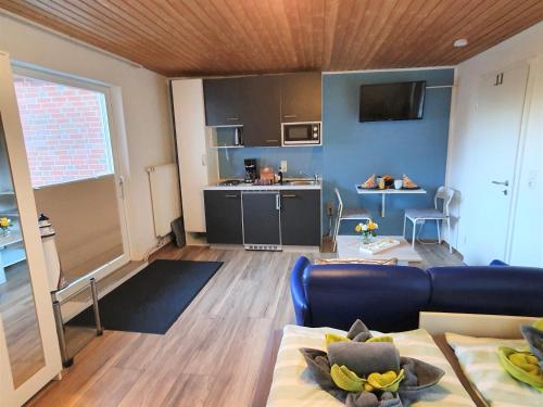 een woonkamer met een bank en een keuken bij Apartment Nordseeblick in Norddeich