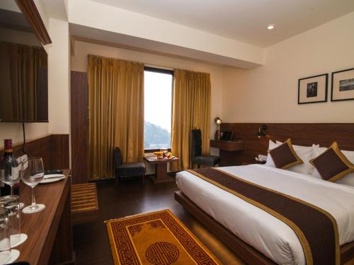 ein Hotelzimmer mit einem großen Bett und einem Schreibtisch in der Unterkunft Indra Mandala,Gangtok - AM Hotel Kollection in Gangtok