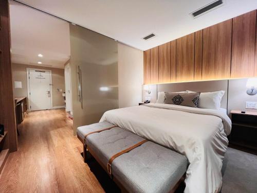a bedroom with a large bed with a bench next to it at MRG- Exclusive Gramado Loft 1D - 10 minutos do Centro in Gramado