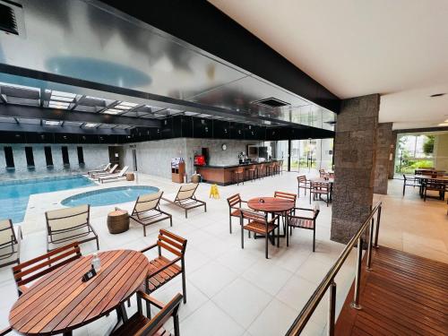une terrasse intérieure avec des tables et des chaises ainsi qu'une piscine dans l'établissement MRG- Exclusive Gramado Loft 1D - 10 minutos do Centro, à Gramado