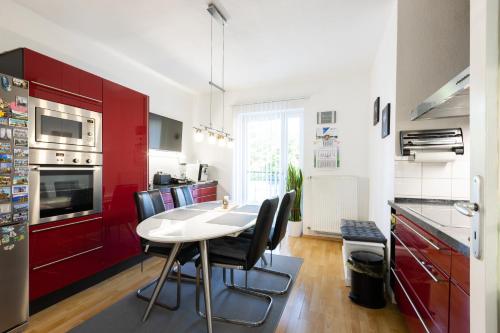 een keuken met rode kasten en een witte tafel en stoelen bij ZV2001 Private Apartments & Rooms near Exhibition Ground (room agency) in Hannover