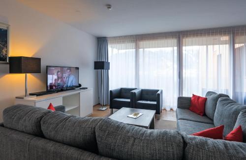 a living room with a large couch and a television at Residence Bellevue - incl Summercard in Zell am See