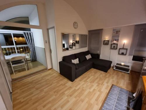 uma sala de estar com um sofá preto e um piso de madeira em Bellyenmer Gruissan em Gruissan