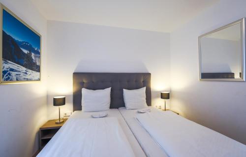 a bedroom with a large white bed with two lamps at Residence Bellevue - incl Summercard in Zell am See
