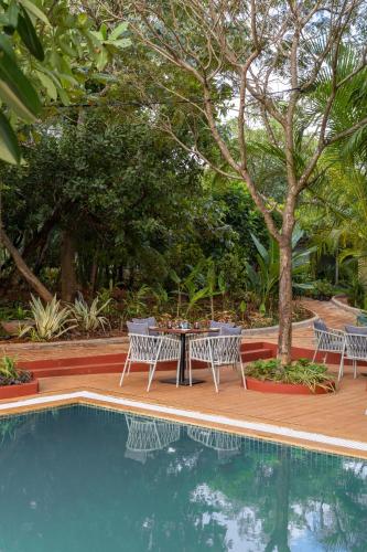a table and chairs next to a swimming pool at LaRiSa Resort & Spa, Ashwem in Mandrem