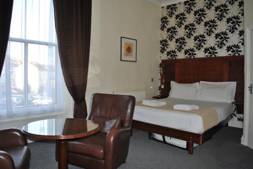 a bedroom with a bed and a chair and a table at Town House Rooms in Hastings