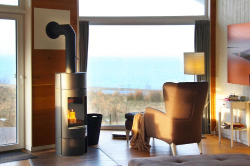 Una sala de estar con chimenea con una silla y una ventana. en Ferienhaus Skagen, en Steinbergkirche