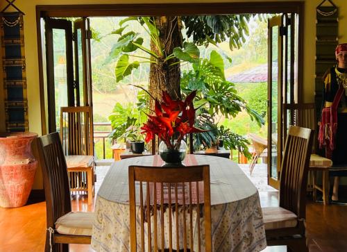 a dining room table with a vase of flowers on it at Kanlaya's Eyrie, Luxury Homestay in Pang Mapha