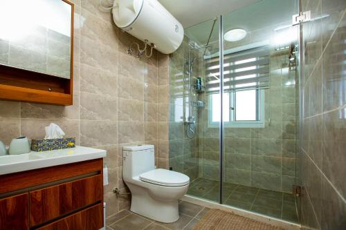 a bathroom with a toilet and a glass shower at 3-Bedroom Apartment in Tema - Chez Akwasi in Tema