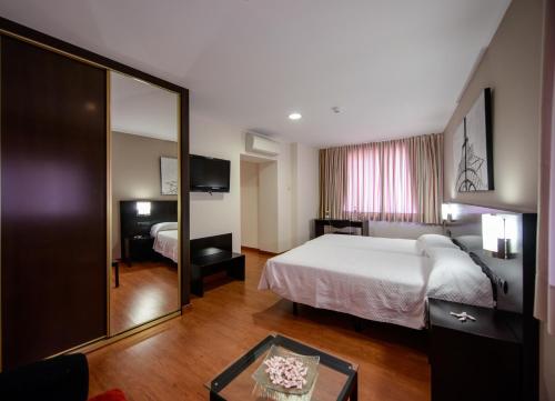 オスピタル・デ・オルビゴにあるHotel El Paso Honrosoのベッドと鏡が備わるホテルルーム