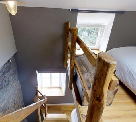 ein Schlafzimmer mit einem Bett und zwei Fenstern in einem Zimmer in der Unterkunft Le repaire des amoureux in La-Roche-en-Ardenne