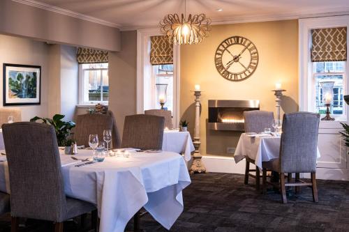 a restaurant with two tables and a clock on the wall at The Porlock Weir Hotel in Porlock