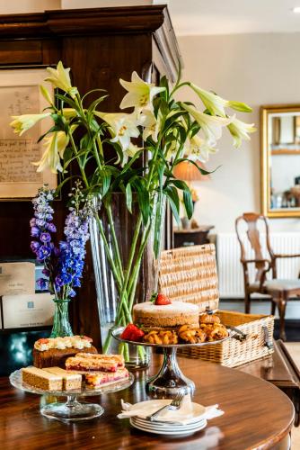 a table with some cakes and flowers on it at The Porlock Weir Hotel in Porlock