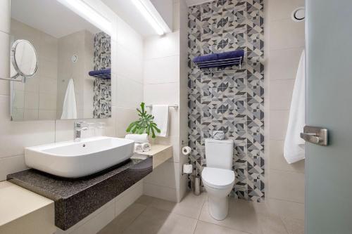 a white bathroom with a sink and a toilet at Sofianna Resort & Spa in Paphos