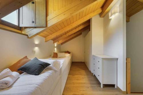 1 dormitorio con 2 camas y techo de madera en Duplex Campodios Villanua en Villanúa
