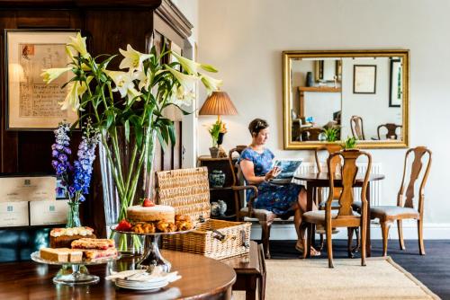 The Porlock Weir Hotel في بورلوك: امرأة تجلس على طاولة في غرفة المعيشة