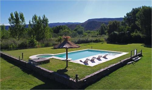 a pool with chairs and an umbrella in a field at Cabañas Posada del Angel in Valle Grande