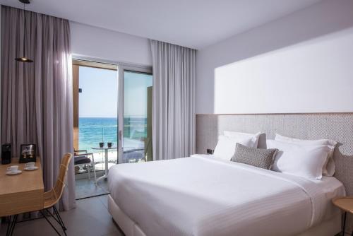 a hotel room with a bed and a view of the ocean at Enorme Ammos Beach Resort in Malia