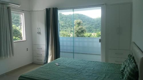 um quarto com uma cama e uma grande janela em Casa com vista linda em Maricá