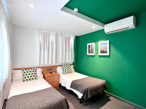 Habitación con 2 camas y pared verde. en Hostal Apolo, en Barcelona