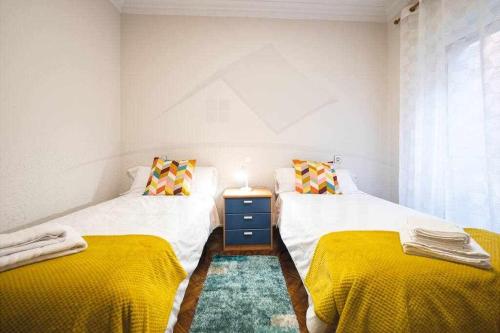 2 aparte bedden in een kamer met gele lakens bij Las Nieves Apartamento in Gijón