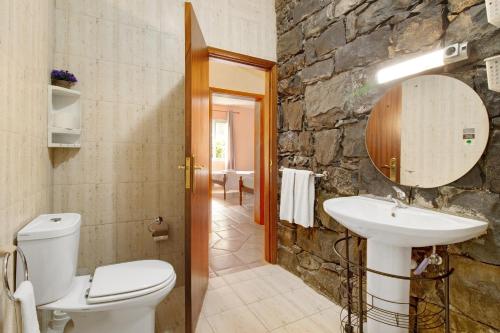 a bathroom with a toilet sink and a stone wall at Casa Cristina in Junqueira