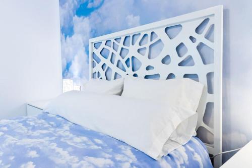 uma cama com lençóis brancos e almofadas num quarto em Apartamento completo a 5 minutos estación tren. em Córdoba