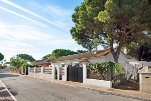 a white fence in front of a house with a tree at El Mirlito in Roche