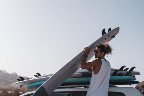 a man holding a surfboard on top of a pile of surfboards at Wavy Days in Tamraght Ouzdar