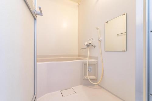a shower in a white bathroom with a mirror at Sapporo Residential Juno in Sapporo