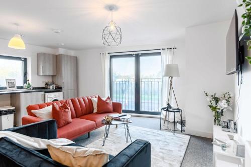 uma sala de estar com um sofá vermelho e uma cozinha em LiveStay-New Private Apartment Building Minutes From Heathrow em Slough