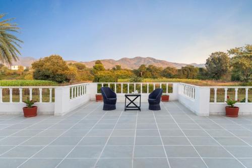 a patio with chairs and mountains in the background at Jass Bagh Home stay Udaipur I swimming pool I wedding I 946o1o3906 in Udaipur