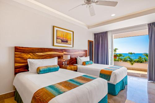 two beds in a room with a view of the ocean at Blue Horizon 103 in Puerto Vallarta