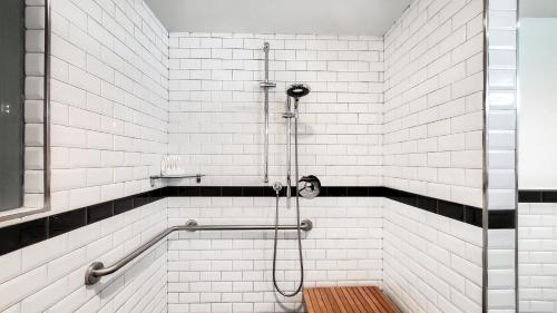 a white tiled bathroom with a shower with a wooden floor at Archer Hotel New York in New York