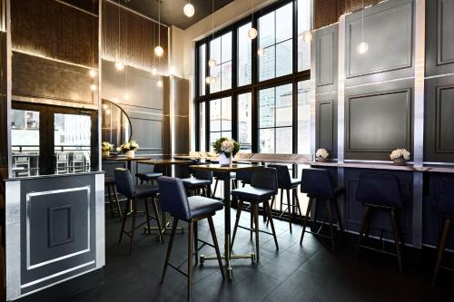a restaurant with a bar with chairs and tables at Archer Hotel New York in New York